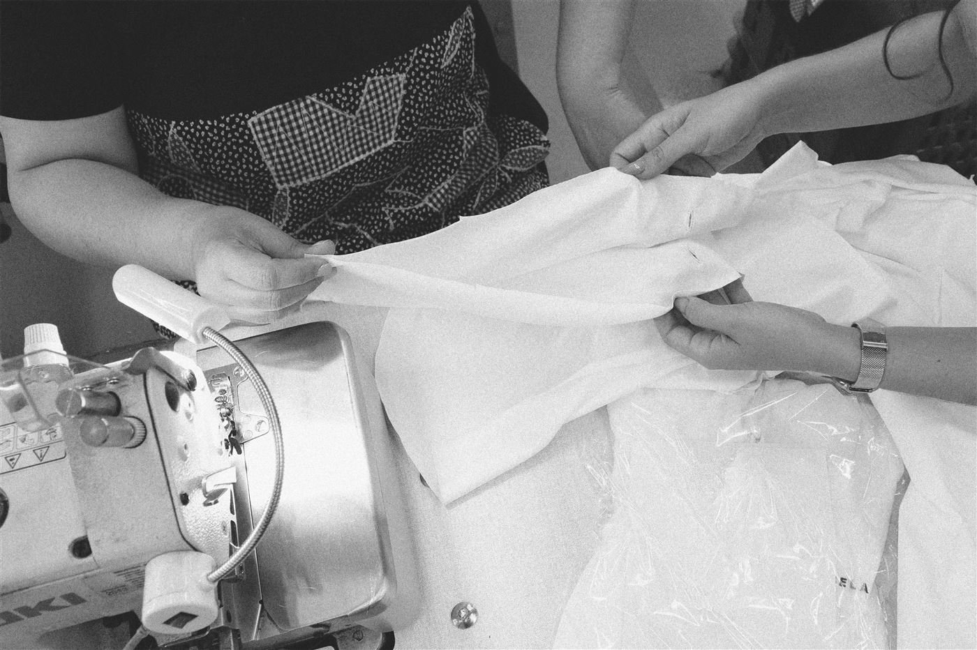 Hands guiding fabric through an industrial sewing machine